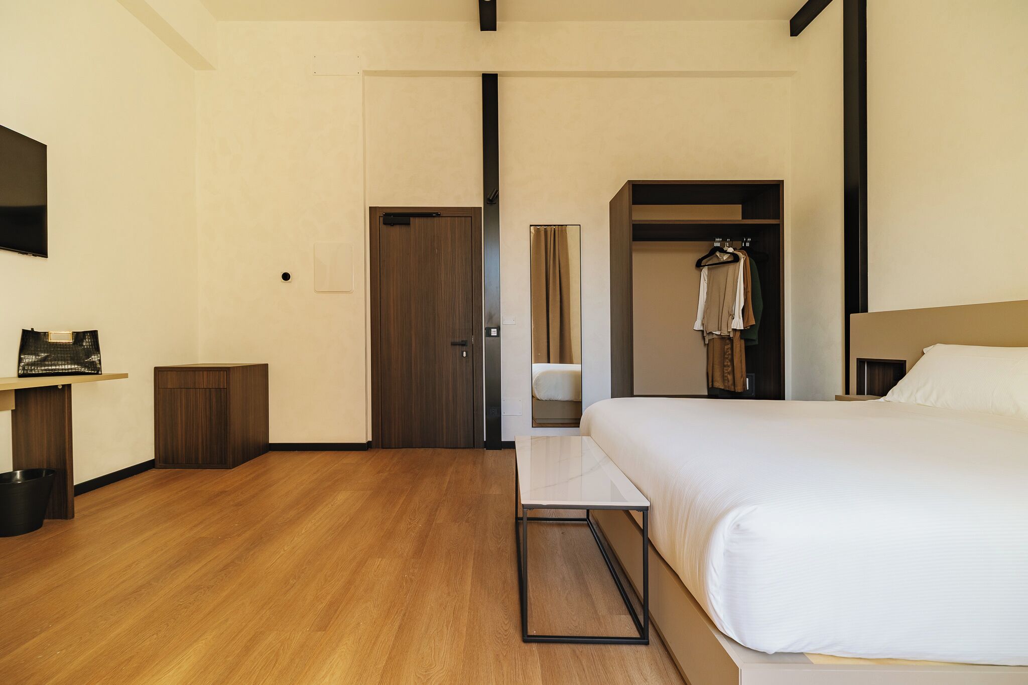 Une chambre d’hôtel avec un lit, une petite table, une armoire et un miroir.