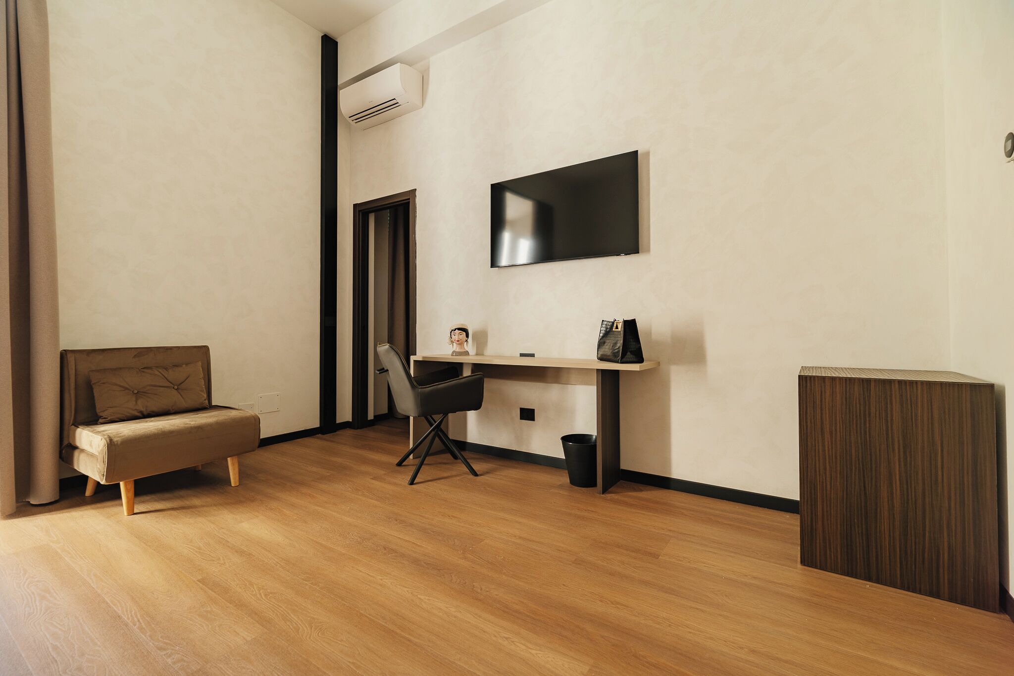 Ein modernes Zimmer mit einer Couch, einem Schreibtisch, einem Stuhl, einem Fernseher und einem Schrank.