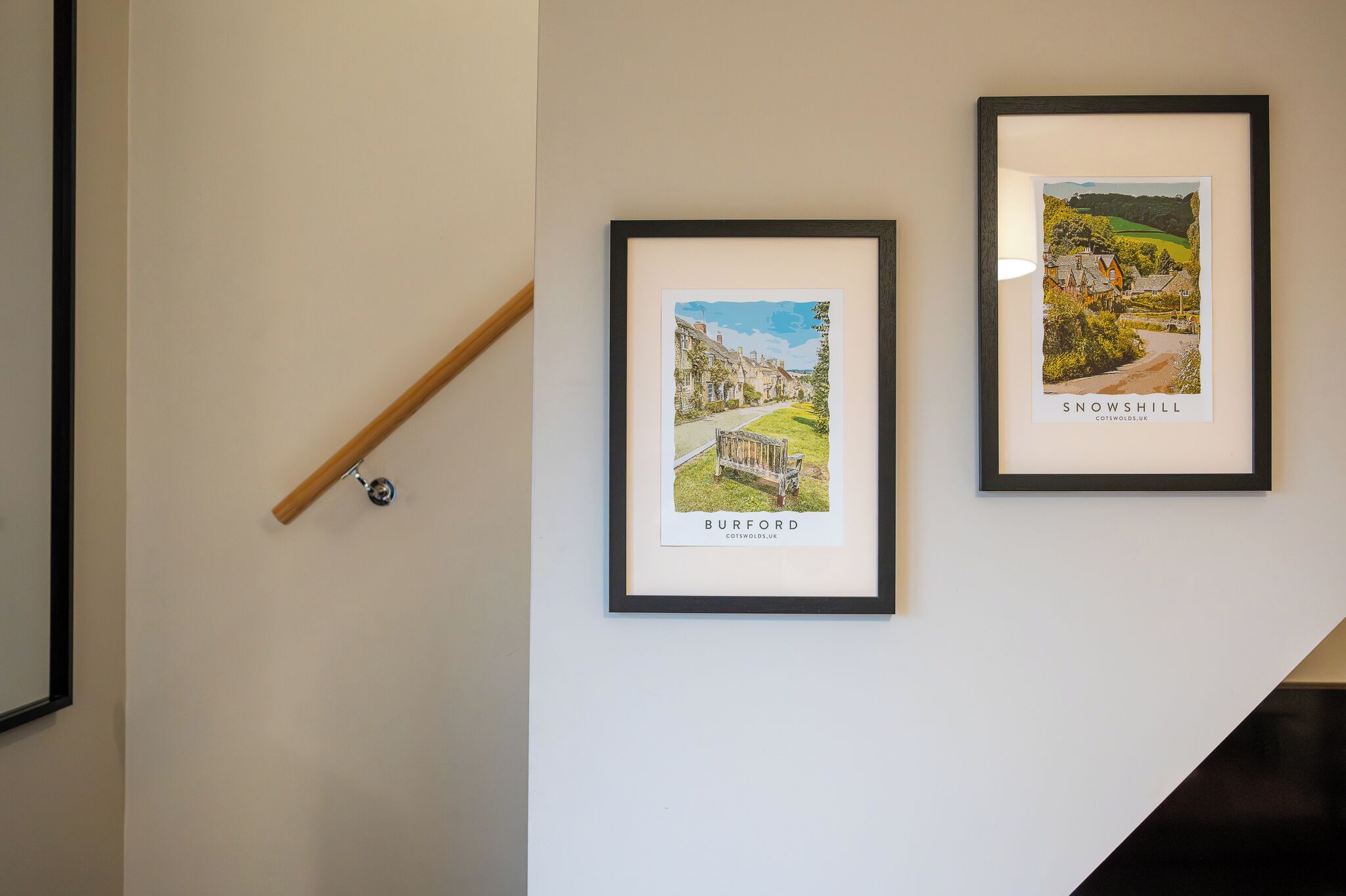 Two framed pictures of towns on a wall.