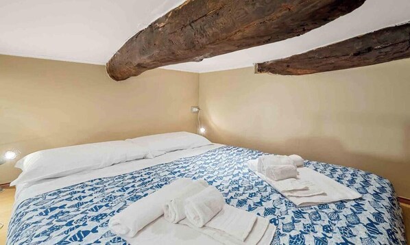 A room with a bed, a nightstand, and a wall-mounted light. - Ideal for a couple or a single traveler, just a few steps from the crystal clear sea, typical restaurants and panoramic paths that will lead you to discover breathtaking views. La Cantinetta encloses in its small space all the necessary comfort and the r (Tellaro)