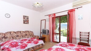 Ein Schlafzimmer mit zwei Betten, einem Fernseher und Blick ins Freie.