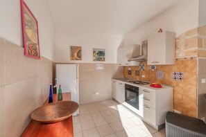 Eine kleine Küche mit Kühlschrank, Herd und gefliestem Spritzschutz.