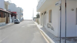 A street with buildings, a parked car, and a sign reading 'ghandi vi'. - Apartment 'Monolocale Eddy By Salentolimit' with Balcony and Air Conditioning (Torre Lapillo)