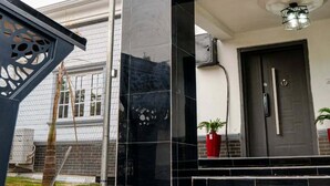 Ein modernes Gebäude mit dunkler Fassade, einer sichtbaren Tür und einem kleinen Blumentopf nahe dem Eingang.
