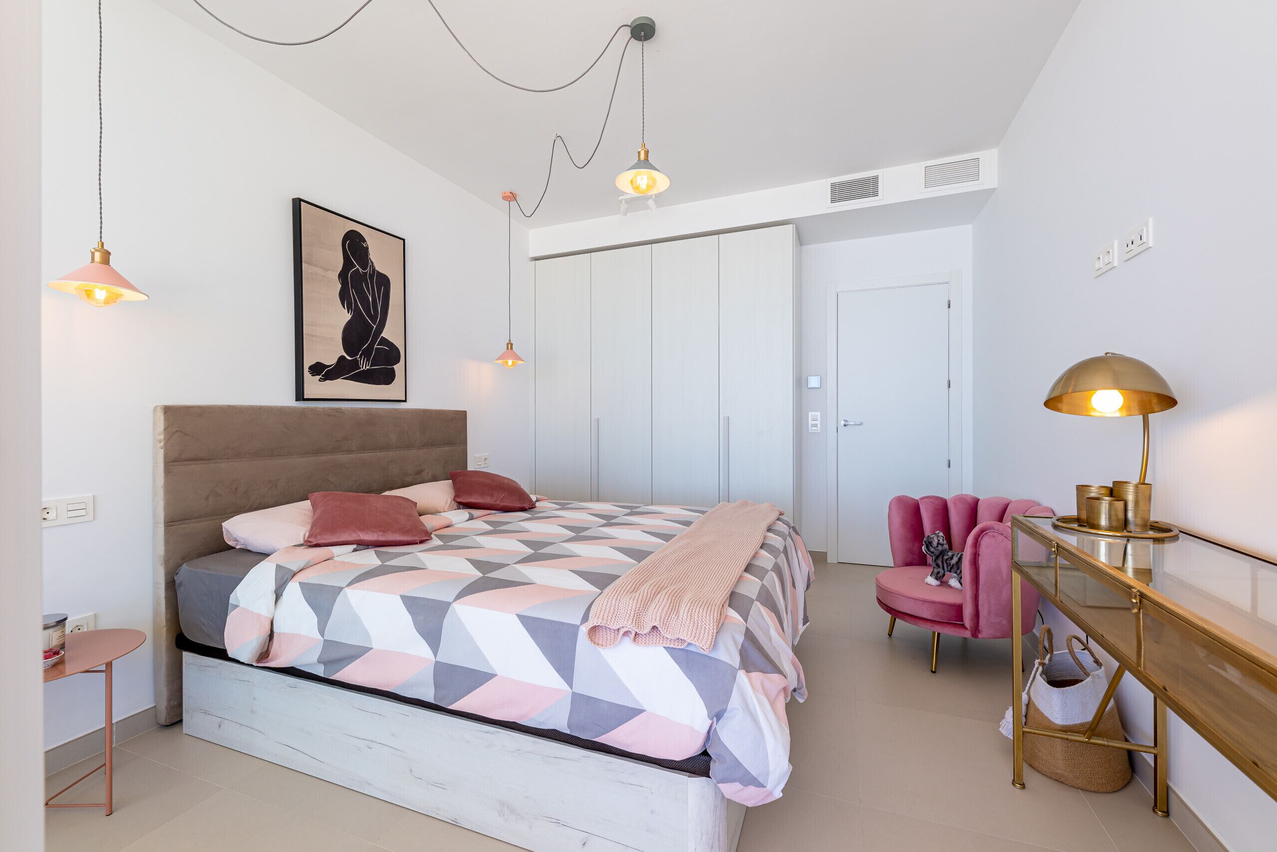 A modern bedroom with a bed, bedside table, chair, and a desk.