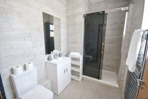 A modern bathroom with a toilet, sink, and shower area. - Sleek 2BR Liverpool Apt City Centre Location (Liverpool)