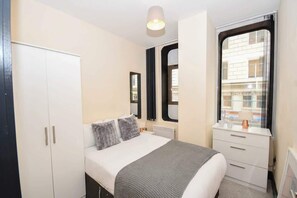 A bedroom with a bed, a wardrobe, a window, and a bedside table. - Sleek 2BR Liverpool Apt City Centre Location (Liverpool)