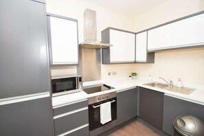 A modern kitchen with a built-in microwave, oven, and sink. - Sleek 2BR Liverpool Apt City Centre Location (Liverpool)