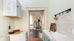 A narrow kitchen with a white refrigerator, a sink, and a tiled backsplash. - Romeo & Giulietta Rooms: double room in historic Bosa (Bosa)