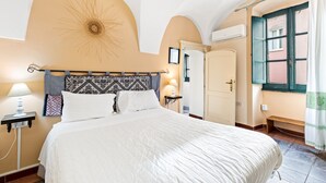 Une chambre d’hôtel avec un lit, une table de chevet avec une lampe, une horloge murale et une fenêtre avec des rideaux.
