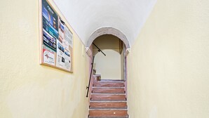 Un escalier étroit doté d’une main courante, une affiche accrochée au mur et un plafond blanc.
