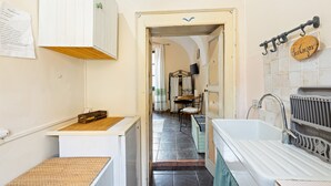 Un couloir étroit mène à une salle de bain équipée d’une baignoire, d’un lavabo et d’un miroir.