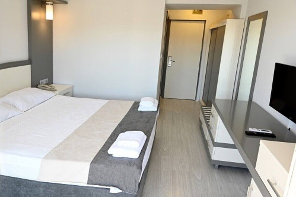 Een hotelkamer met een bed, nachtkastjes, een televisie en een spiegel.