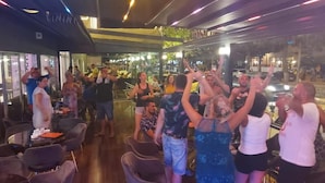 A group of people dancing in a restaurant with a bar area and seating. - HOTEL ROXX ROYAL (Kusadasi)