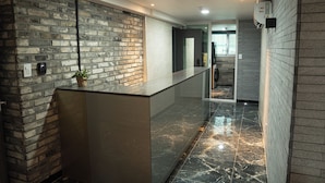 A reception area with a brick wall, a marble floor, and a modern reception desk.