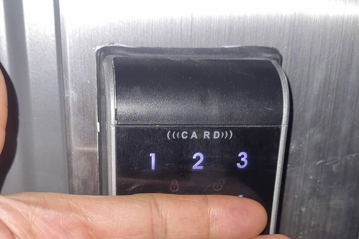 A hand pressing a numeric keypad on an elevator control panel.