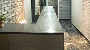 A modern hallway with a marble floor, a reception desk, and a brick wall.