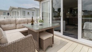 A balcony with a wicker sofa, a glass table, and a bottle of wine. - No. 4 Fistral (Newquay)