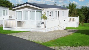 A white mobile home with a fenced porch and a gravel driveway. - No. 4 Fistral (Newquay)
