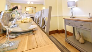A dining area with a wooden table set for two, a chandelier, and a clock on the wall. - Llwyn Derw (Talybont)