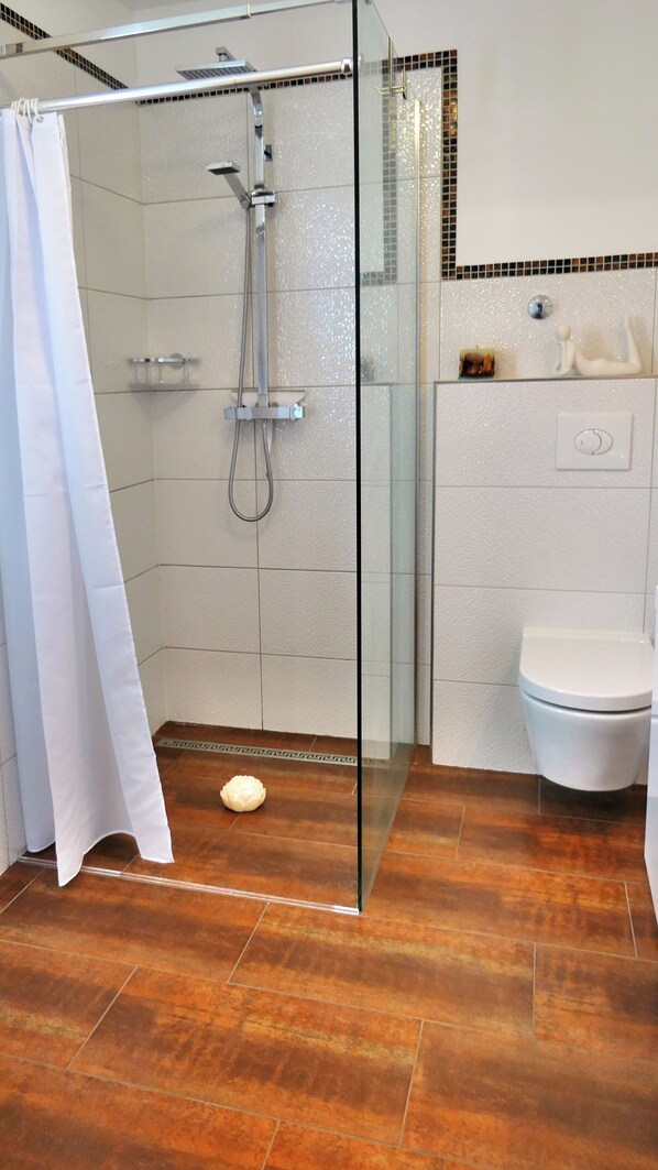A modern bathroom with a glass-enclosed shower, a white toilet, and a tiled floor.