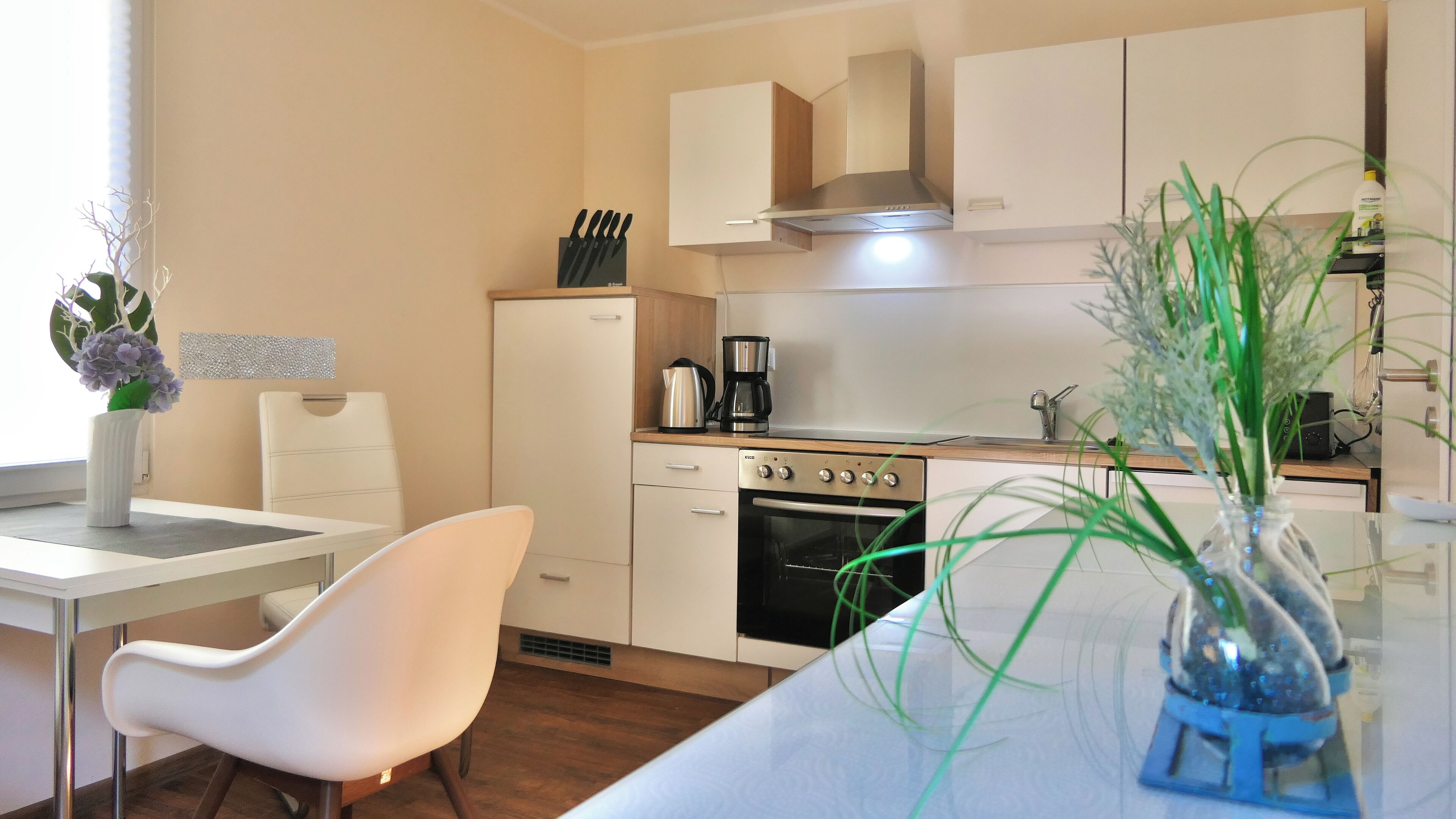 A modern kitchen with white cabinets, a built-in oven, and a coffee maker.