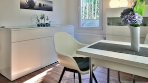 Een moderne eethoek met een witte tafel, een witte stoel en een vaas met bloemen.