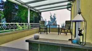 Een balkon met twee stoelen, een tafeltje en decoratieve accessoires.
