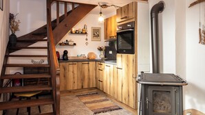 Une cuisine avec des meubles de rangement en bois, un fourneau et un escalier en bois.