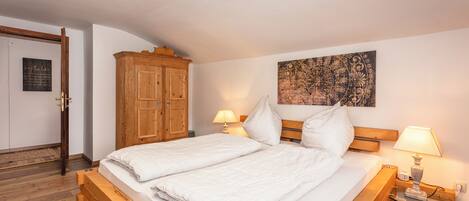 Un dormitorio con una cama de madera, dos lámparas de noche, un armario de madera y un tapiz colgado en la pared.