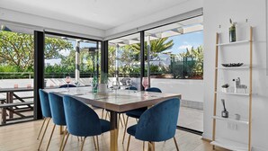 Un espace repas moderne avec une grande table, des chaises bleues et une cloison en verre.