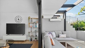 Un salon moderne avec un téléviseur à écran plat, un canapé, une table basse et une table à manger en verre.