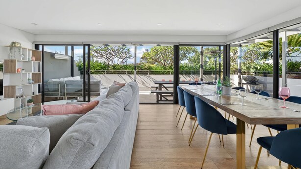Un salon moderne avec un grand canapé gris, une table à manger avec des chaises bleues et une table basse en verre.