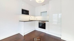 Una cocina moderna con armarios blancos, microondas, fregadero y horno.