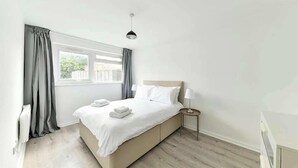 A neatly arranged bedroom with a bed, bedside tables, and a window with curtains. - The Elden - No.4 (London)
