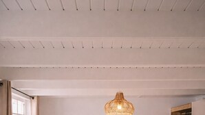 Een slaapkamer met een bed, twee bedlampjes, een hanglamp, een ronde wanddecoratie en een houten garderobe.