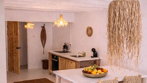 Eine Küche mit einer zentralen Kochinsel, Holzküchenstühlen, einer Obstschale und hängenden Leuchten.