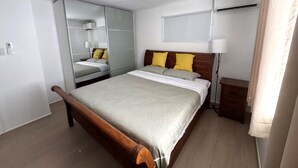 Een slaapkamer met een houten bed, een spiegel, een nachtkastje en een kledingkast.
