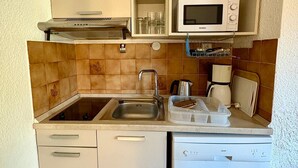 Una cucina compatta con lavello, forno a microonde ed elettrodomestici.