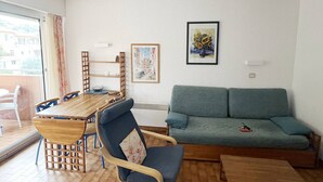 Un soggiorno con un tavolo da pranzo in legno, sedie blu, un divano verde e un quadro appeso al muro.