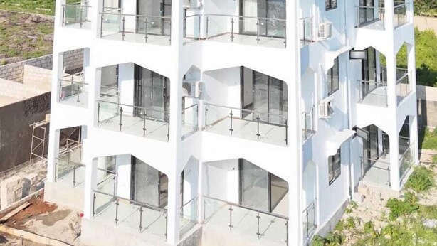 Un edificio a più piani con tetto piatto, ampie finestre e balconi.