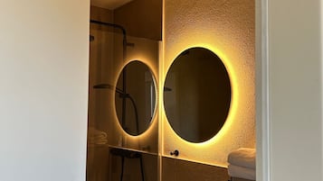Een moderne badkamer met een grote spiegel, een rond wastafel en een douche.