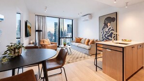 Un apartamento moderno con comedor, sofá, cocina y ventanas amplias con vistas a la ciudad.