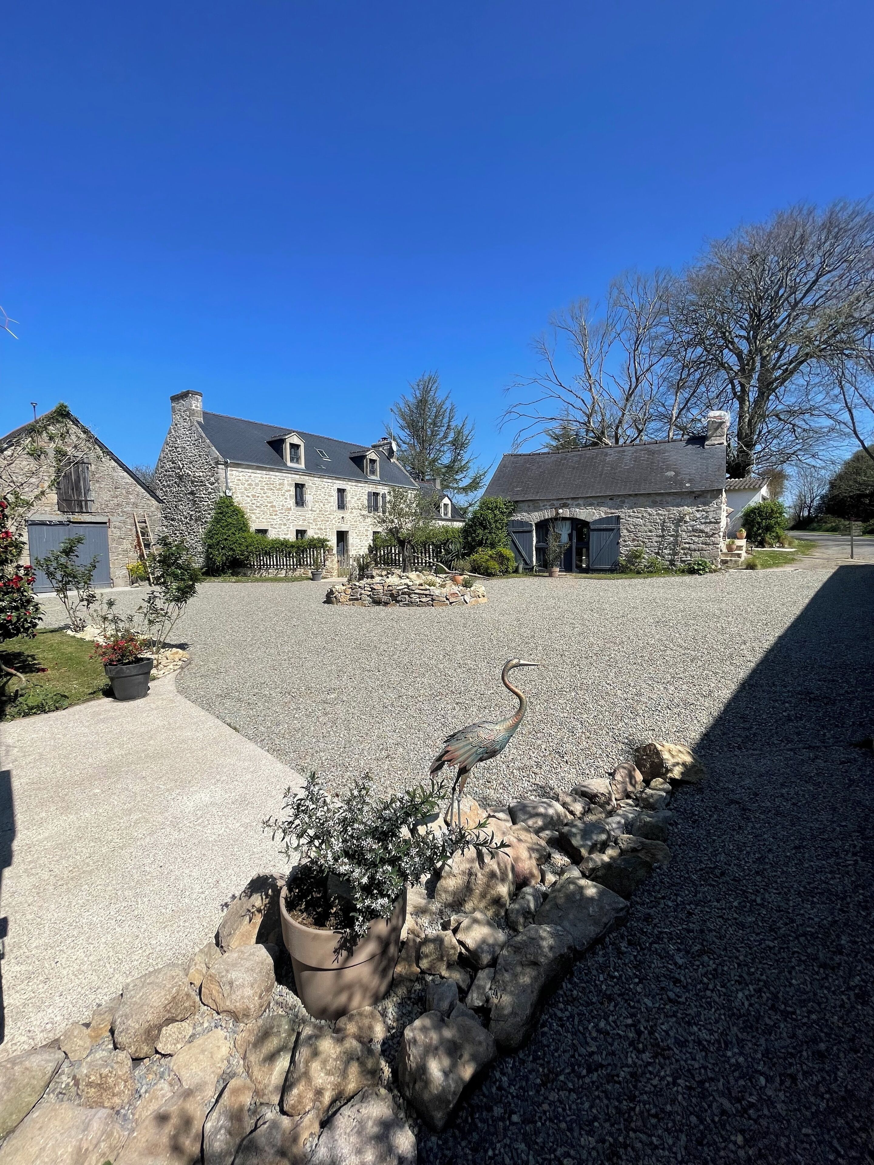 A stone house with a gravel driveway and a bird on the rocks.