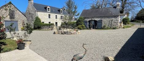 A stone house with a gravel driveway and a bird on the rocks.