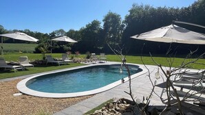 A swimming pool with lounge chairs and umbrellas, surrounded by a landscaped garden and trees. - Chambre Raphaël, a jewel in the Bay of Douarnenez, 10 minutes from the beaches (Pouldergat)