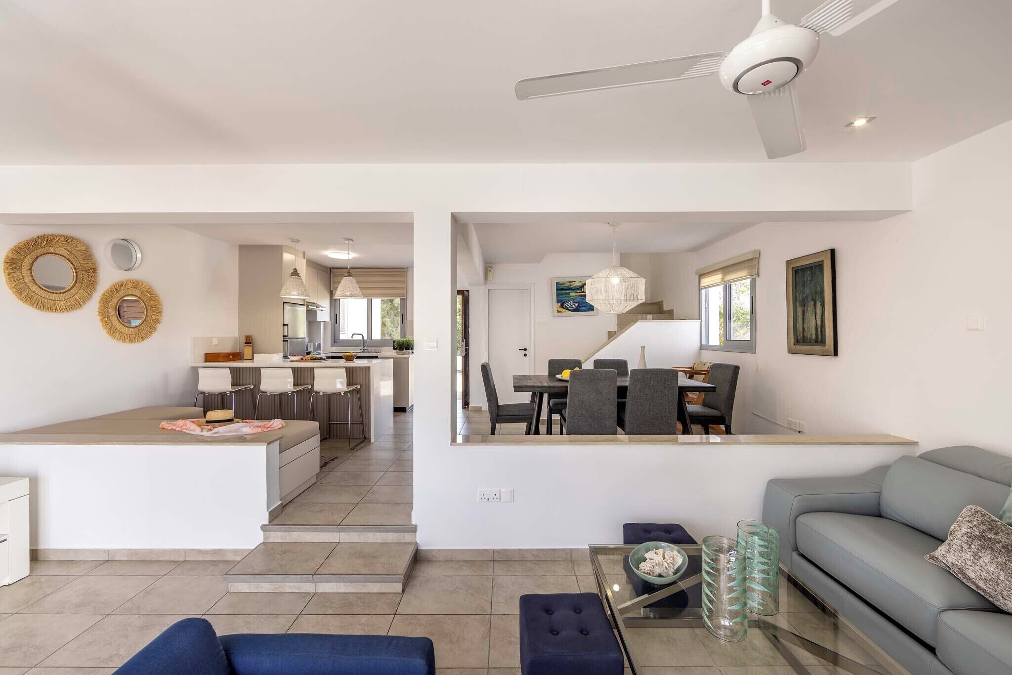 A modern open-plan living area with a kitchen, dining space, and a sofa.