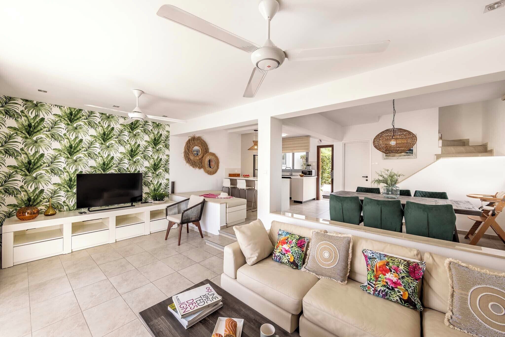 A spacious living area with a TV, sofa, and dining area.