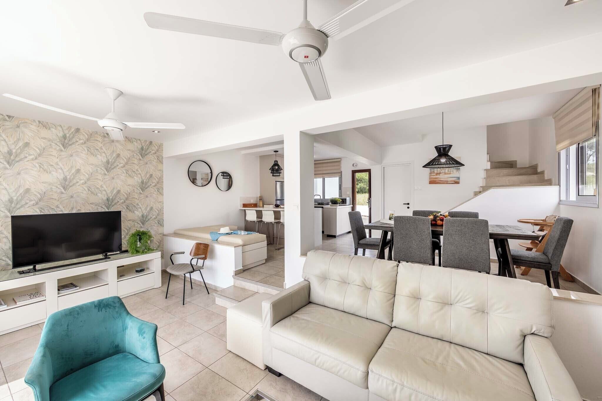 Una sala de estar moderna con sofá, televisión y ventiladores de techo.