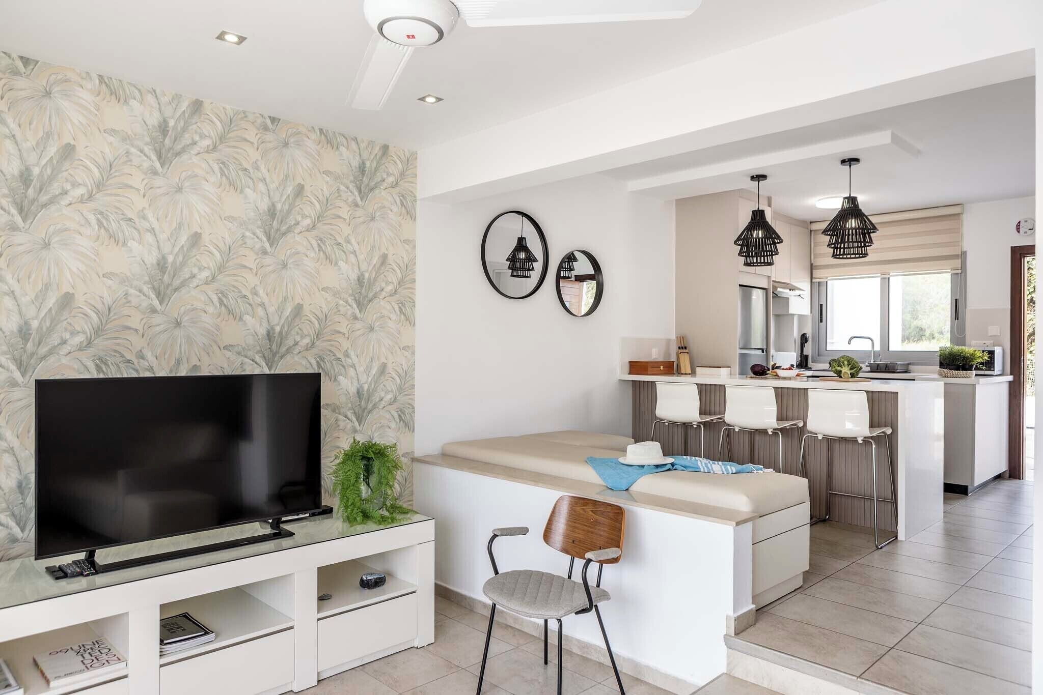 A modern kitchen with a central island, white cabinetry, and pendant lighting.